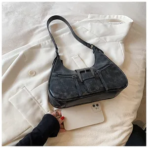 Détails du sac croissant noir vintage avec boucle en métal et zips sur une veste blanche