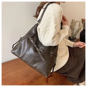 Close-up of a large brown vintage tote bag with metal buckles and texture detail