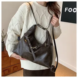 Close-up of vintage brown PU leather shoulder bag with gold hardware and buckle detail