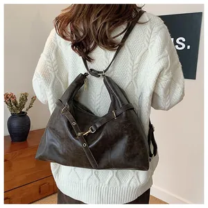 Detail of a large dark brown leather backpack showing retro texture and metallic buckle
