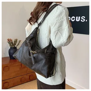 Detail of dark brown vintage leather hobo bag with metal eyelet straps and gold buckle