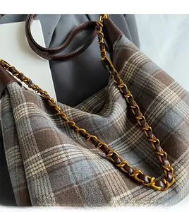 Détail de la bandoulière en chaîne dorée et cuir brun sur le sac à motif à carreaux