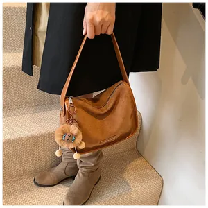 Détail du sac à bandoulière vintage en daim marron avec pendentif en peluche et fermeture éclair