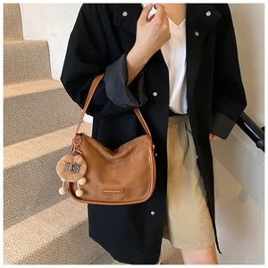 Gros plan d'un sac hobo en daim marron avec un porte-clé ours peluche et logo