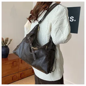 Detail view of large dark brown hobo bag with vintage leather texture and gold buckle