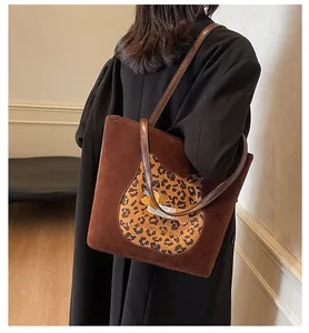 Detail view of brown suede tote bag featuring leopard patch and long leather straps