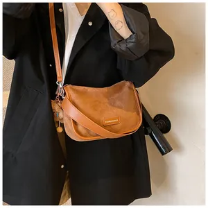 Détail du sac demi-lune en daim marron avec bandoulière en cuir et charm peluche