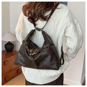 Detail of dark brown leather backpack with retro texture worn over a white sweater