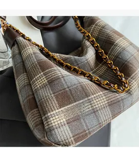 Détail du sac seau à carreaux en laine montrant le tissu et la chaîne dorée