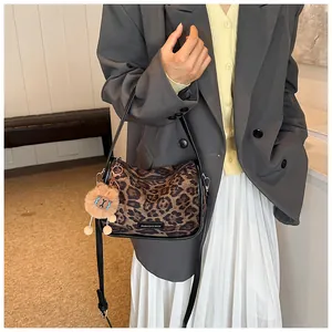 Détail du sac en suédine imprimé léopard avec breloque en peluche et bandoulière noire