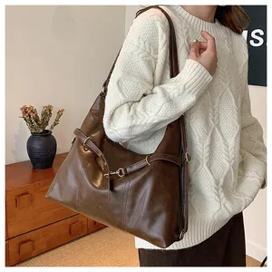 Close-up of deep brown leather shoulder bag with adjustable straps and metal buckles