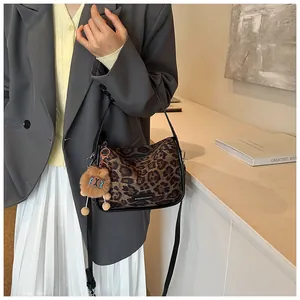 Détail du sac à bandoulière en daim léopard avec un porte-clés lion en peluche mignon