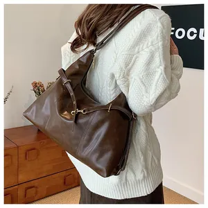 Detail of a large dark brown tote bag with decorative straps and metal buckles for women
