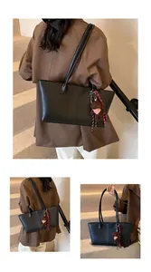 Detail van zwarte leren shopper met een pluche beertje en een gestreepte strik