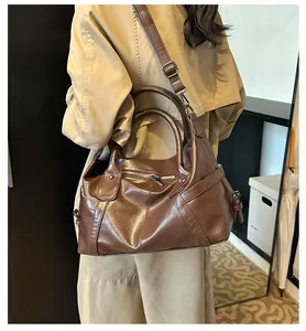 Detail of brown leather tote bag showing geometric stitching and silver metal zippers