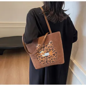 Detail of a brown suede tote bag featuring a leopard cat silhouette and dog embroidery