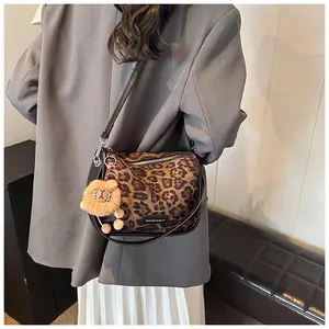 Détail du sac bandoulière à imprimé léopard avec un porte-clés lion en peluche