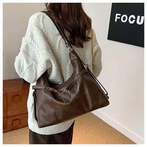 Detail view of large brown vintage tote bag in soft matte leather on model's shoulder