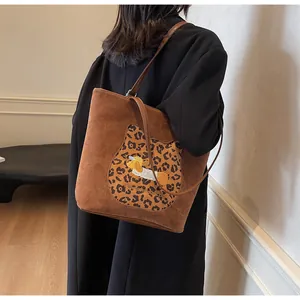 Detail of a brown suede tote bag featuring a leopard cat and dachshund dog embroidery