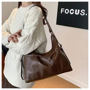Detail of dark brown vintage leather shoulder bag with metallic buckle and soft texture