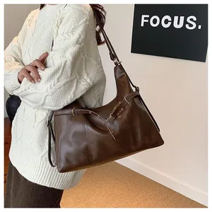 Close-up of deep brown leather tote bag featuring gold buckle detail and smooth finish