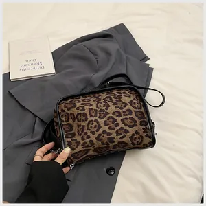 Vue détaillée du sac bandoulière en suédine léopard avec bordures en cuir noir