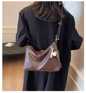 Rear view of model wearing a dark brown bucket tote bag with sporty baseball charms