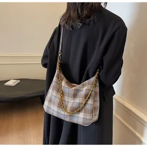 Détail du sac hobo avec motif à carreaux tissé, chaîne dorée et bandoulière en cuir