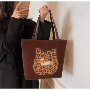 Detail of dark brown suede tote bag with leopard cat patch and honeyhenworld embroidery