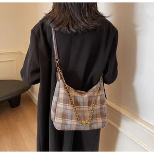 Détail du motif à carreaux bleu et marron d'un sac sous l'aisselle avec chaîne dorée