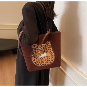 Detail of a large brown suede tote bag featuring a unique leopard cat embroidery patch