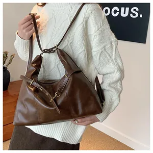 Close-up of dark brown leather tote bag with vintage gold ring buckle and adjustable strap