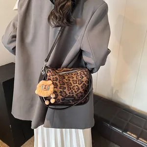 Sac à bandoulière rétro léopard en daim avec pendentif lion porté par un mannequin