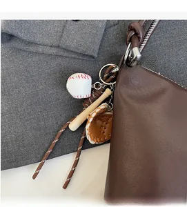Detail of baseball charm set with mini bat and glove on a brown leather bag