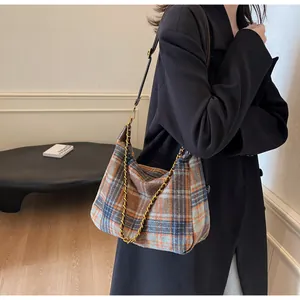 Détail du sac hobo à carreaux rétro avec chaîne dorée et texture de tissu tissé