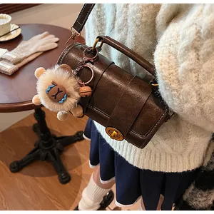 Sac polochon rétro marron avec breloque alpaga en peluche dans un café chaleureux