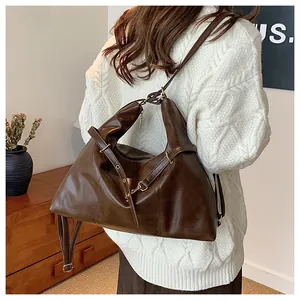 Detail of soft dark brown leather tote bag with adjustable strap and metal hardware