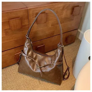 Close-up of vintage brown leather hobo bag featuring matte texture and golden buckle detail