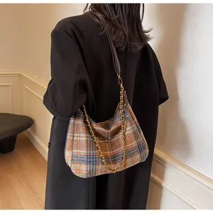 Détail du sac bandoulière en laine à carreaux avec chaîne dorée et lanière en cuir