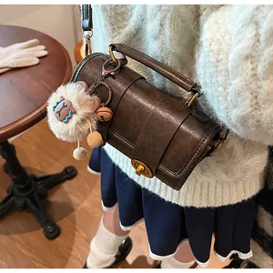 Détail d'un sac polochon marron foncé avec fermoir doré et pendentif en peluche