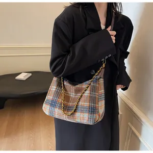 Détail du sac à bandoulière vintage à carreaux avec sangle en cuir et chaîne sur mannequin