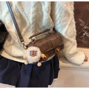 Détail du sac cylindrique marron vintage avec boucles et breloque mouton doux