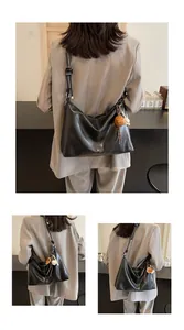 Detail of black leather hobo bucket bag with contrast stitching and baseball charm