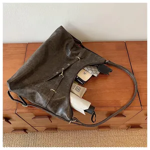 Detailed close-up of brown vintage leather tote with decorative straps and gold hardware