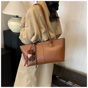 Bruine kunstleren shopper met beertje hanger gedragen door model in modern interieur