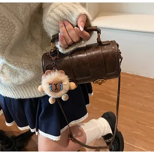 Détail du sac polochon rétro marron foncé avec fermoir vintage et breloque peluche mignonne