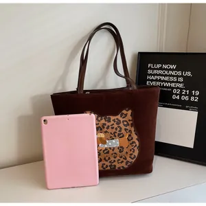 Close-up of brown suede tote bag with leopard cat patch and dog embroidery detail