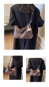 Detail showing dark brown faux leather texture and baseball pendant on a bucket bag