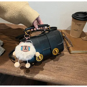 Vue détaillée d'un sac cylindre noir vintage avec boucle dorée et breloque en peluche