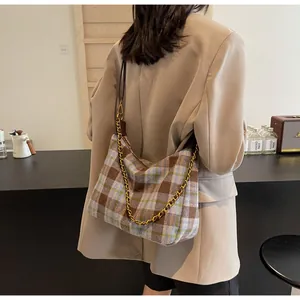 Détail du sac à carreaux vintage avec chaîne dorée et bandoulière en cuir marron